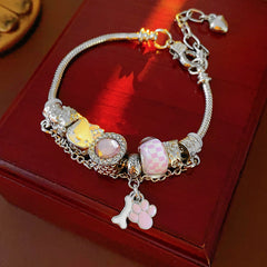Rosy Pawprints Charm Bracelet — silver-tone snake chain with pink crystal bezel, checker enamel bead, cat-with-bow, paw and bone charms in jewelry tray