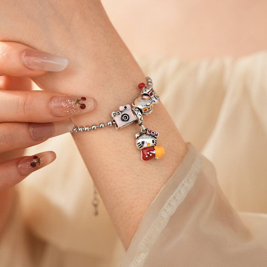 Kawaii Charm Story Bracelet with cartoon cat, burger, camera, and bell charms on silver-tone bead chain