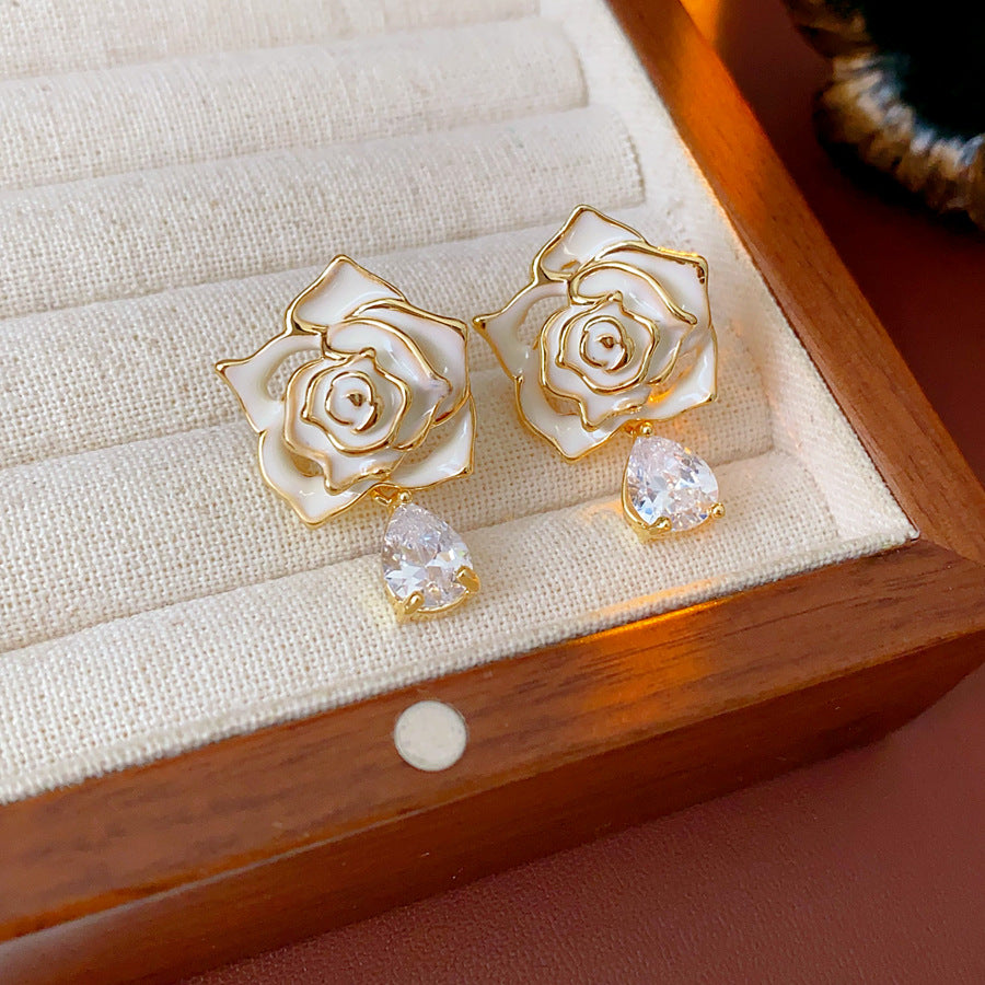 Gold-tone rose stud earrings with ivory and black enamel petals plus teardrop zircon dangles — Gilded Rose Teardrop Studs.