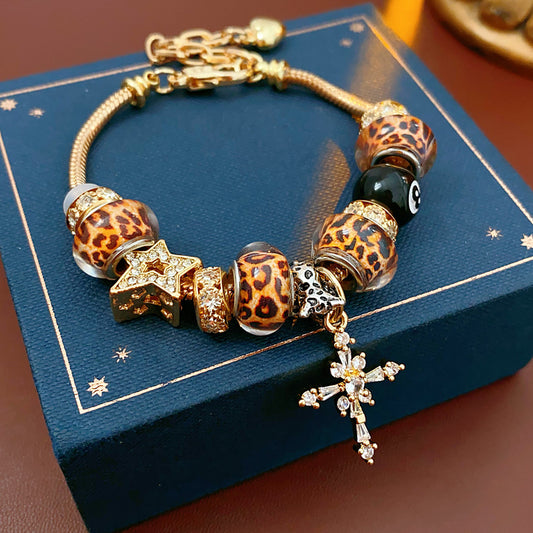 Leopard Cross Luxe Bracelet with leopard-patterned beads, zircon accents, black 8-ball bead, and cross pendant on gold chain