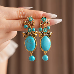 Gold filigree earrings with large turquoise cabochons, crystal accents, and dangling bead — Azure Oasis Turquoise Earrings.