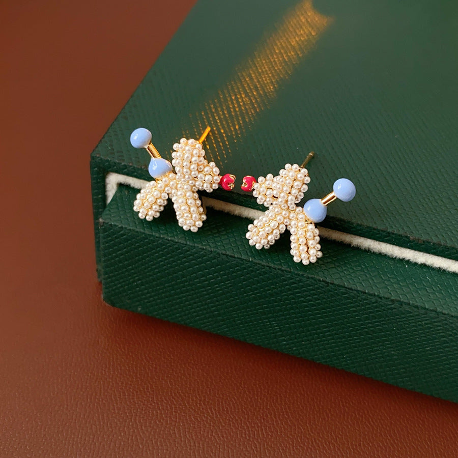 Balloon dog stud earrings crafted from imitation pearls with blue bead details — Playful Poodle Pearl Studs.