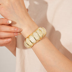 Gold-tone segmented bangle with marbled acrylic dome tiles — Gilded Capsule Resin Bangle.