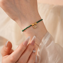 Two variant options of a malachite charm bracelet: beaded green strand with a crystal bloom charm, and a gold-tone chain with malachite accents and a heart pendant — Malachite Charm Bracelet (Variants).
