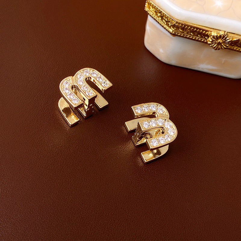 Gold arc “M” stud earrings in pavé crystal and white enamel — Muse Arc Pavé Stud Earrings.