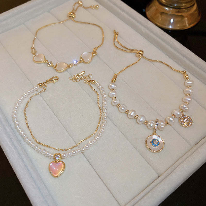 Gold-plated bracelet collection with pearls, cat’s eye stones, and floral motifs