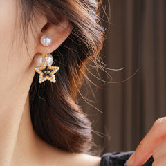 Double-pearl stud earrings with gold-tone butterfly and star charms displayed in a jewelry tray — Double Pearl Charm Studs.