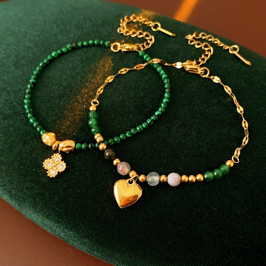 Two variant options of a malachite charm bracelet: beaded green strand with a crystal bloom charm, and a gold-tone chain with malachite accents and a heart pendant — Malachite Charm Bracelet (Variants).