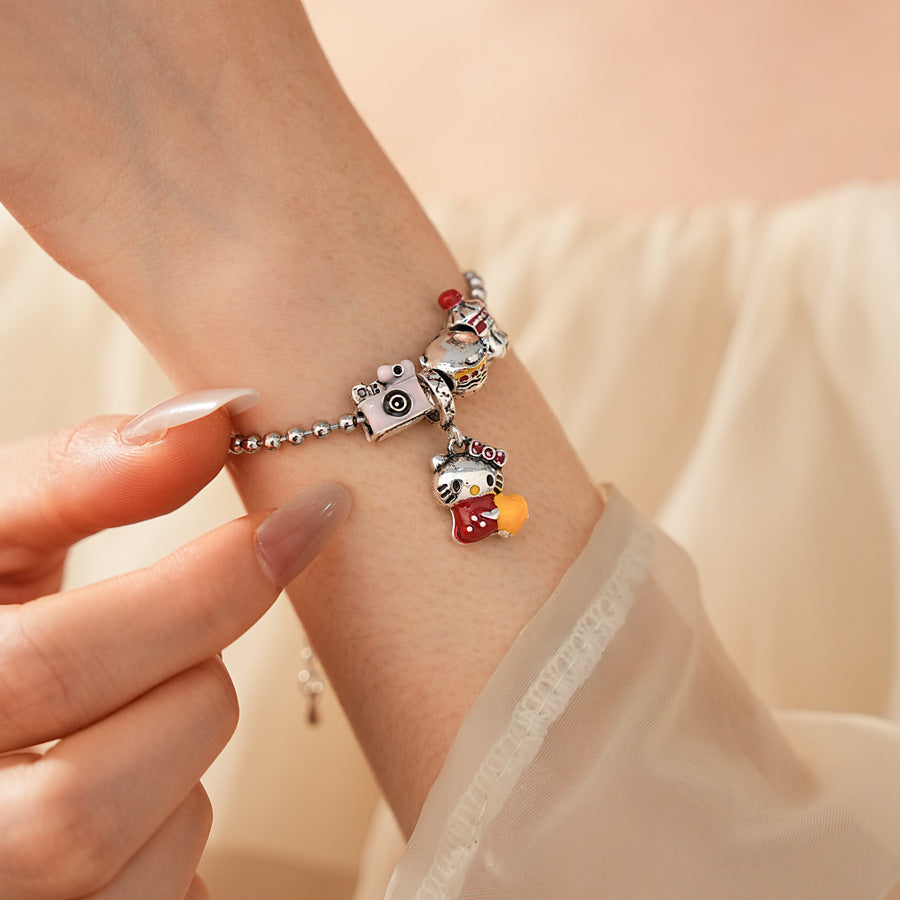 Kawaii Charm Story Bracelet with cartoon cat, burger, camera, and bell charms on silver-tone bead chain