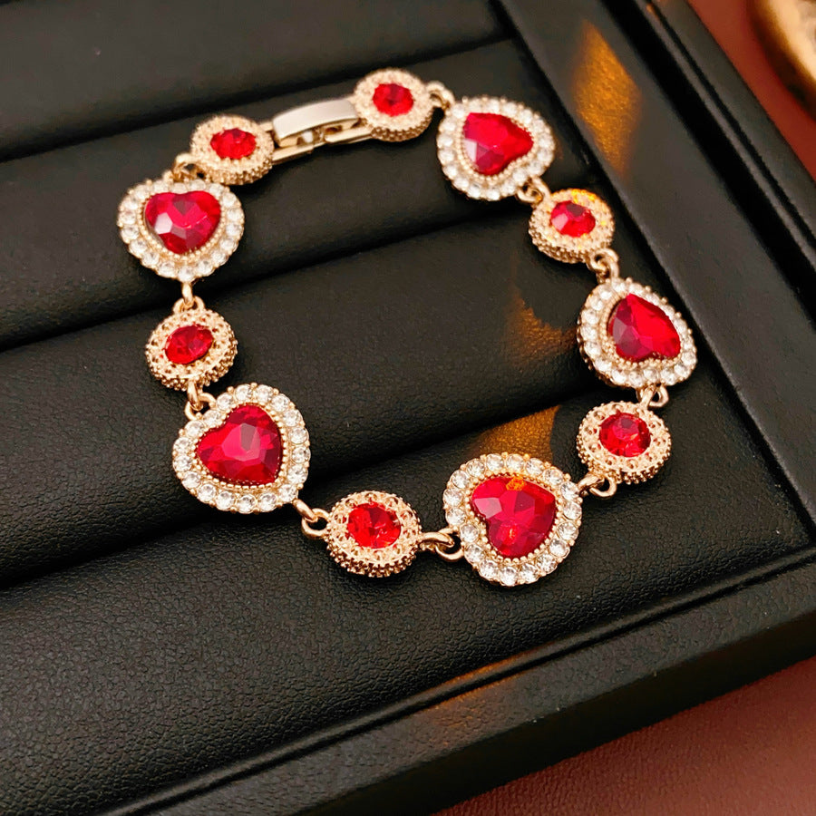 Crimson Heart Luxe Collection with red heart gemstone necklace, bracelet, and earrings, accented with pavé details