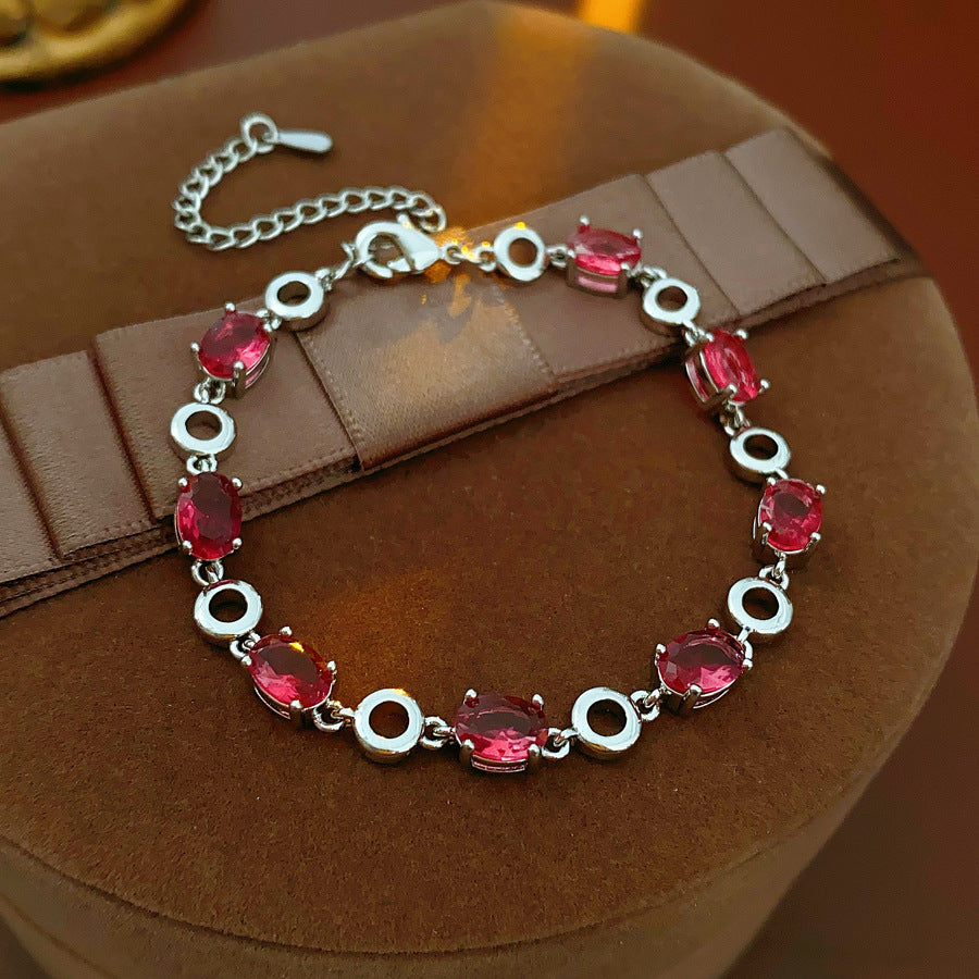 Oval Radiance Zircon Bracelet with silver-tone links and rose zircon stones, displayed on a book background