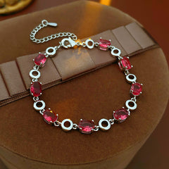 Oval Radiance Zircon Bracelet with silver-tone links and rose zircon stones, displayed on a book background