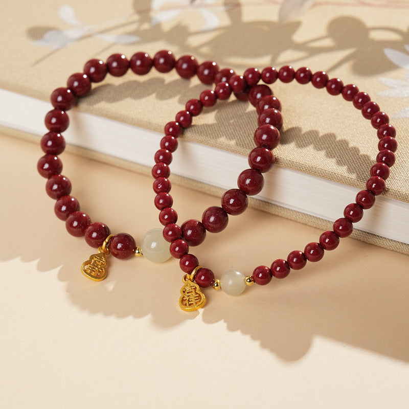 Red cinnabar beaded bracelet with Hetian jade bead and a gold-tone gourd charm.