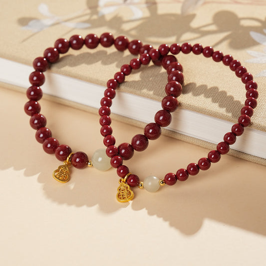 Red cinnabar beaded bracelet with Hetian jade bead and a gold-tone gourd charm.