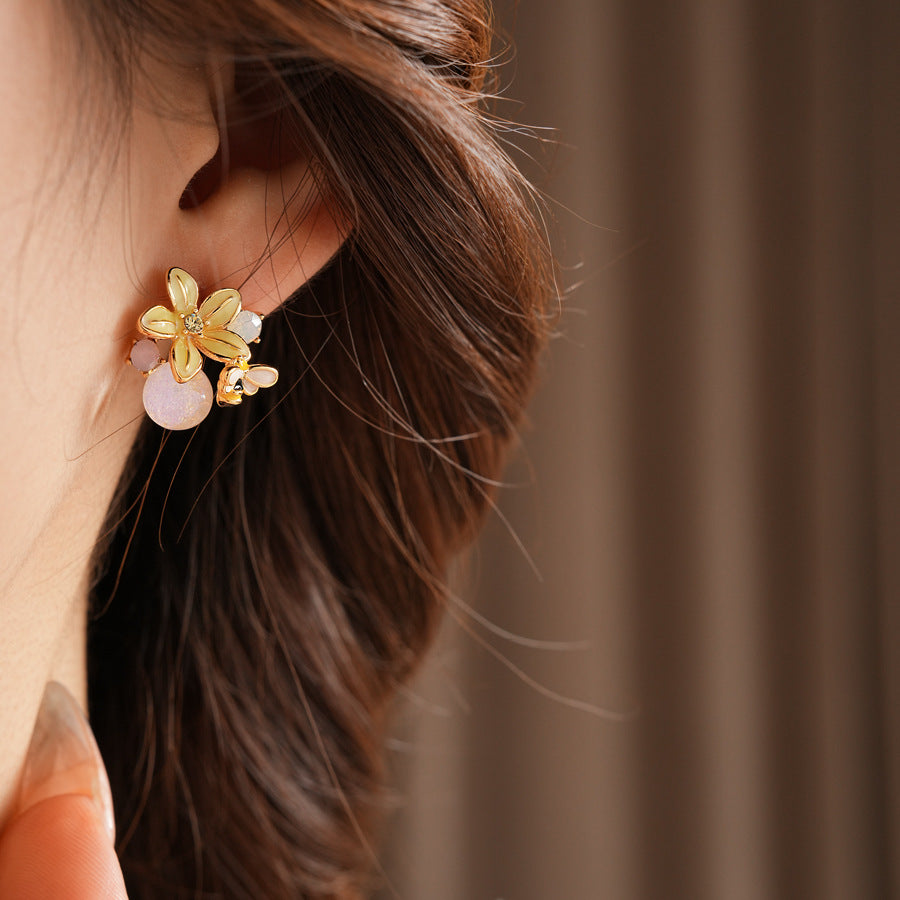 Honeybee Blossom Crystal Stud Earrings — gold flower studs with tiny bee charm and pink crystal orb on black jewelry box