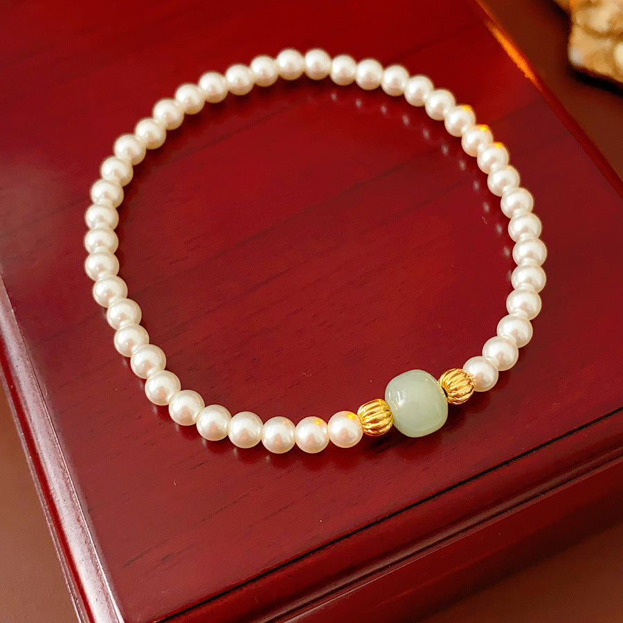 Delicate pearl bracelet with a pale green Hetian jade focal bead and gold-tone spacers — Hetian Jade Pearl Bracelet.