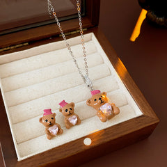 Silver-tone necklace with coffee teddy pendant and pink hat, matching teddy stud earrings with heart crystal — Sweetheart Teddy Crystal Jewelry.