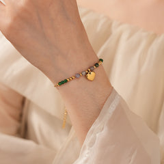 Two variant options of a malachite charm bracelet: beaded green strand with a crystal bloom charm, and a gold-tone chain with malachite accents and a heart pendant — Malachite Charm Bracelet (Variants).