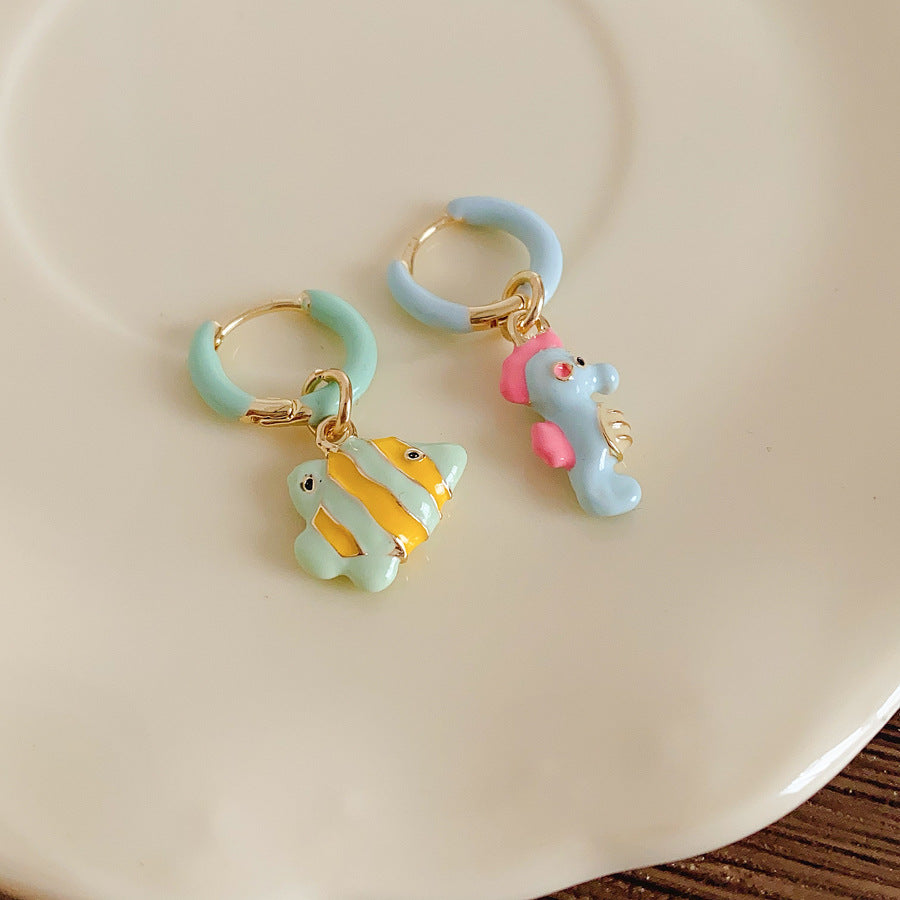 Pastel enamel huggie earrings with mismatched seahorse and striped fish charms — Seafoam Mismatch Ocean Charm Huggies.