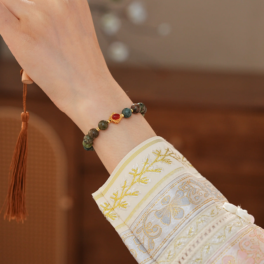 <div class="gz-desc">
  <p>Earthy and refined <strong>natural stone bracelet</strong> combining lush <strong>green ghost</strong> beads with smooth <strong>agate</strong>, accented by a warm red centerpiece and gold-tone spacers for a subtle touch of luxury.</p>

  <h3>Design Story</h3>
  <p>The <strong>Forest Ember Agate Bracelet</strong> evokes the calm of an ancient forest lit by a single ember. Mossy green tones bring grounding energy, while the red accent adds a gentle spark—balance between serenity an