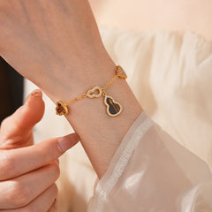 Fortune Gourd Tiger Eye Bracelet with golden gourd motifs, cubic zirconia accents, and natural tiger eye stones, displayed on red wood background