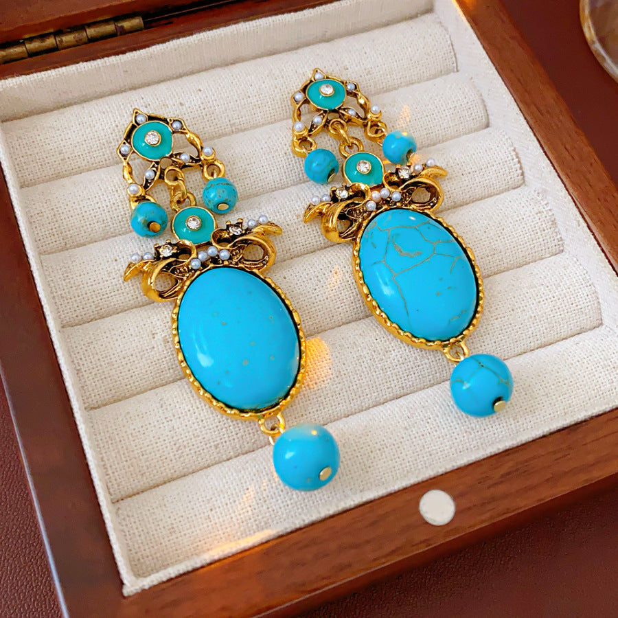 Gold filigree earrings with large turquoise cabochons, crystal accents, and dangling bead — Azure Oasis Turquoise Earrings.