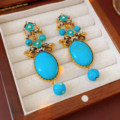 Gold filigree earrings with large turquoise cabochons, crystal accents, and dangling bead — Azure Oasis Turquoise Earrings.