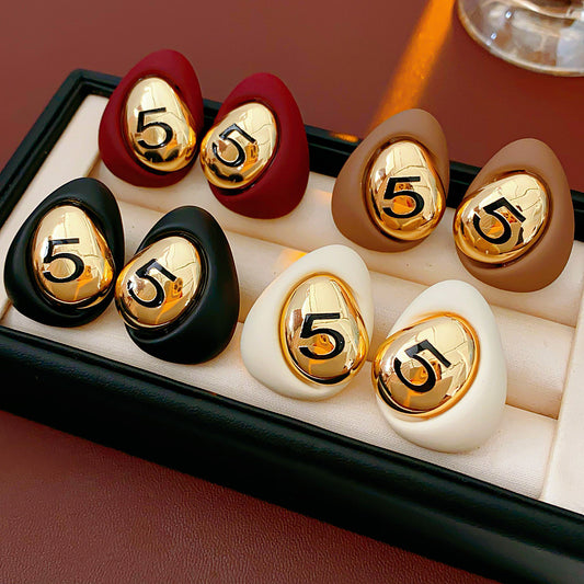 Matte pebble stud earrings with mirrored gold dome engraved with 5 — in white, black, coffee, and red — Gilded Numeral 5 Pebble Studs.
