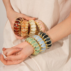 Gold-tone segmented bangle with marbled acrylic dome tiles — Gilded Capsule Resin Bangle.