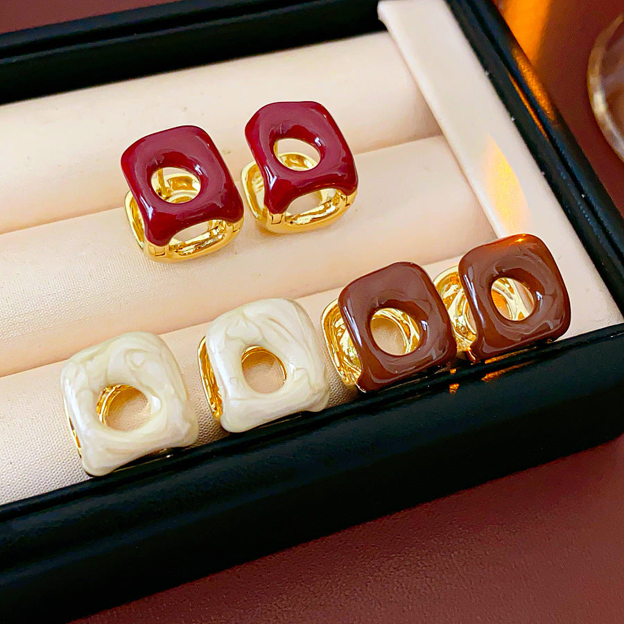 Square pillow ear cuffs with glossy enamel shell and mirrored gold core in white, red, and coffee — Gilded Core Pillow Ear Cuffs.
