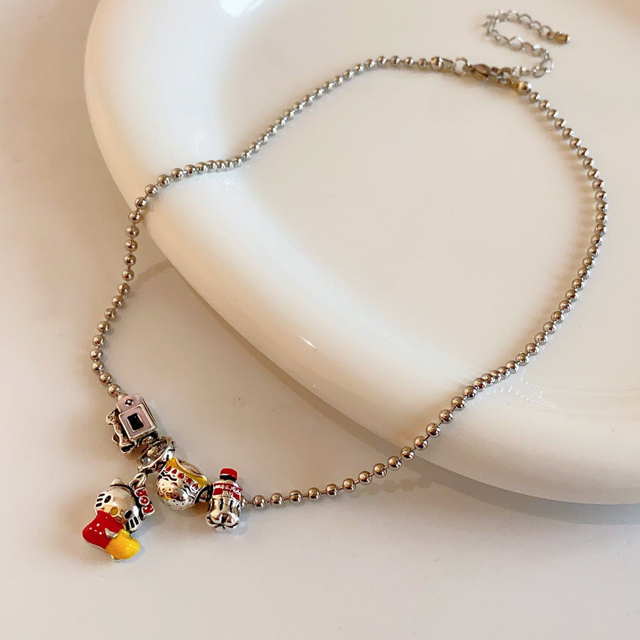 City Voyager Cat Charm Necklace — silver-tone ball chain with enamel cat and camera charms, travel-inspired charm cluster on black pouch