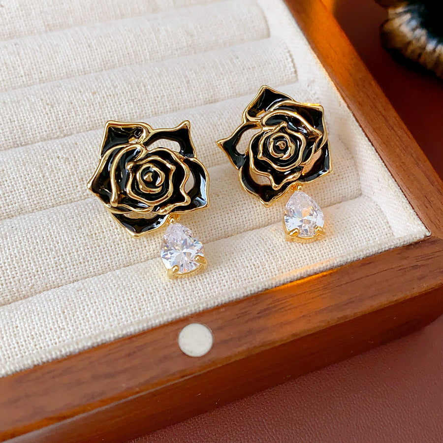 Gold-tone rose stud earrings with ivory and black enamel petals plus teardrop zircon dangles — Gilded Rose Teardrop Studs.