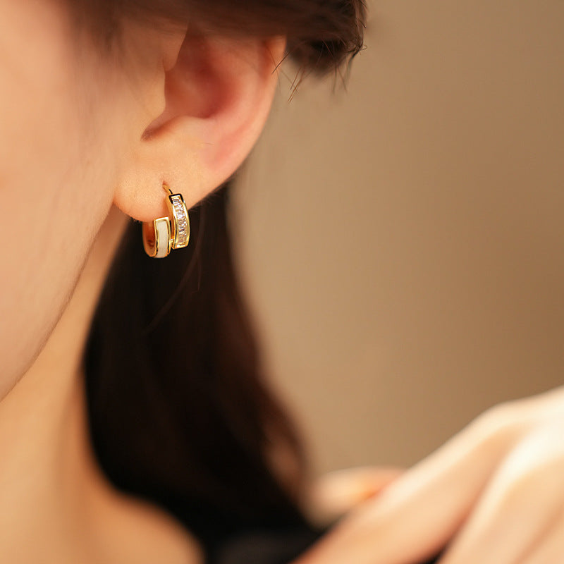 Gold huggie hoop earrings with ivory enamel arc and baguette CZ row — Luna Arc Enamel Baguette Huggies.