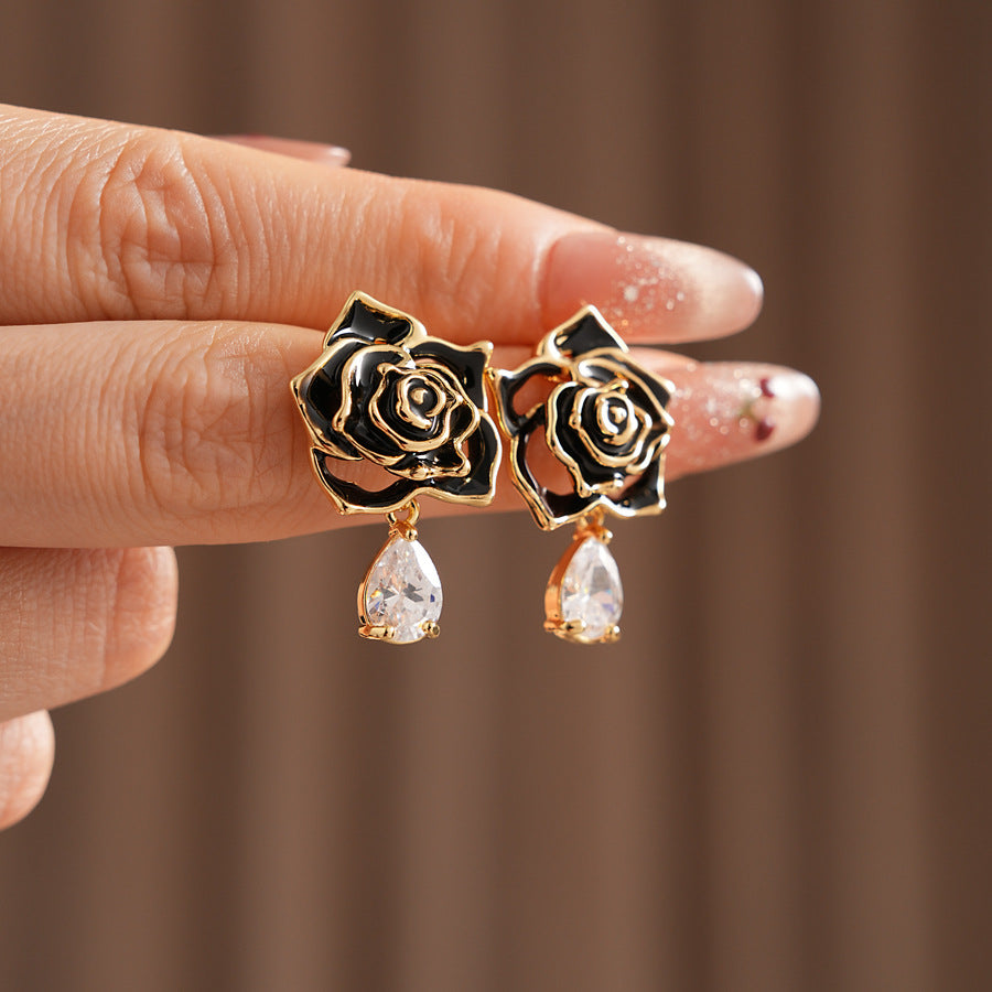 Gold-tone rose stud earrings with ivory and black enamel petals plus teardrop zircon dangles — Gilded Rose Teardrop Studs.